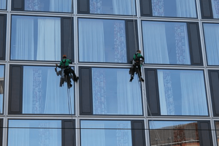 Fenster an einem Hochhaus werden von 2 Personenn gereinigt 